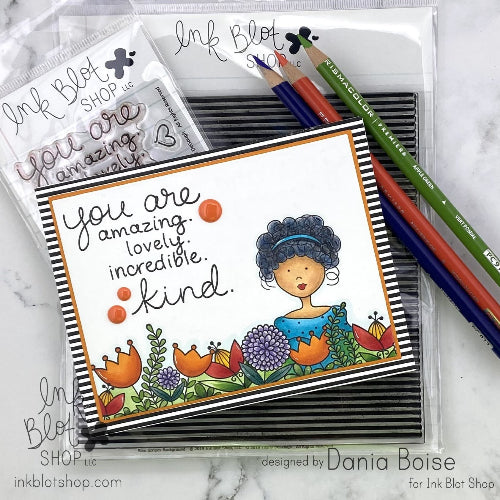 Card with 'You are amazing, lovely, incredible, kind' text and illustrations, surrounded by colored pencils on a marble surface.