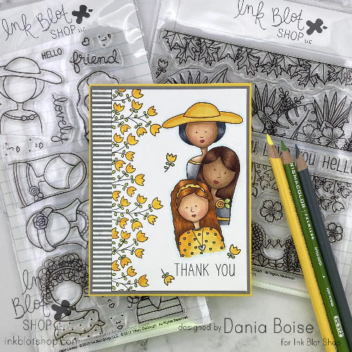 Card with illustrations of three girls and flowers, surrounded by stamp sets and pencils on a white background.
