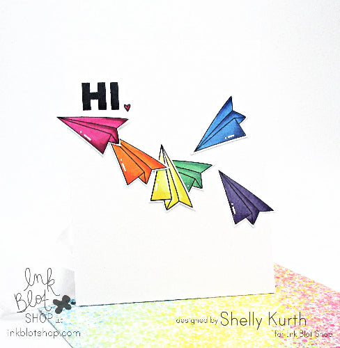 Colorful paper airplanes with 'HI' text on a white background, designed by Shelly Kurth for Ink Blot Shop.
