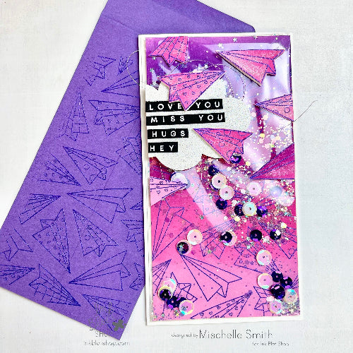 Greeting card with pink paper airplane design and purple envelope on a white background